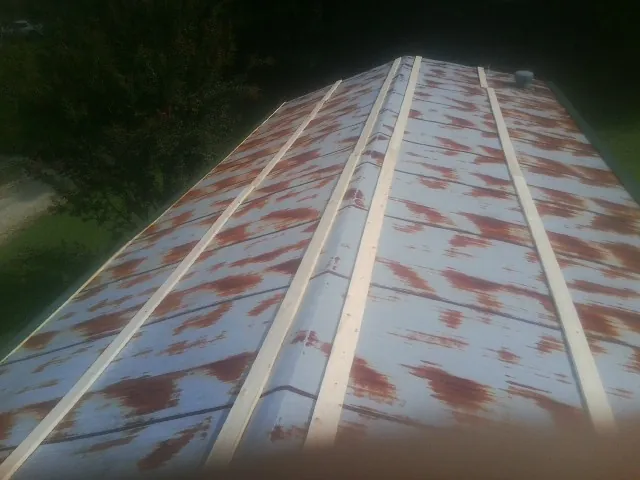 Rusted metal roof panels with new wood purlins before replacement — Storm Damage Roof Repair in Wilder by Roofing Brothers