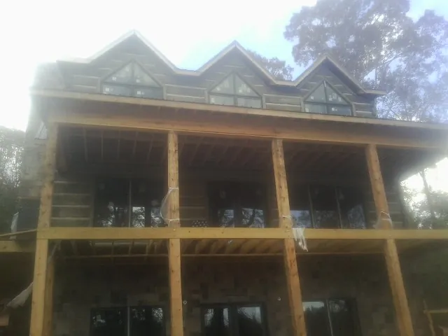 Dormers and porch framing on a large log home under construction — Roof Coating work by our crew in Wilder