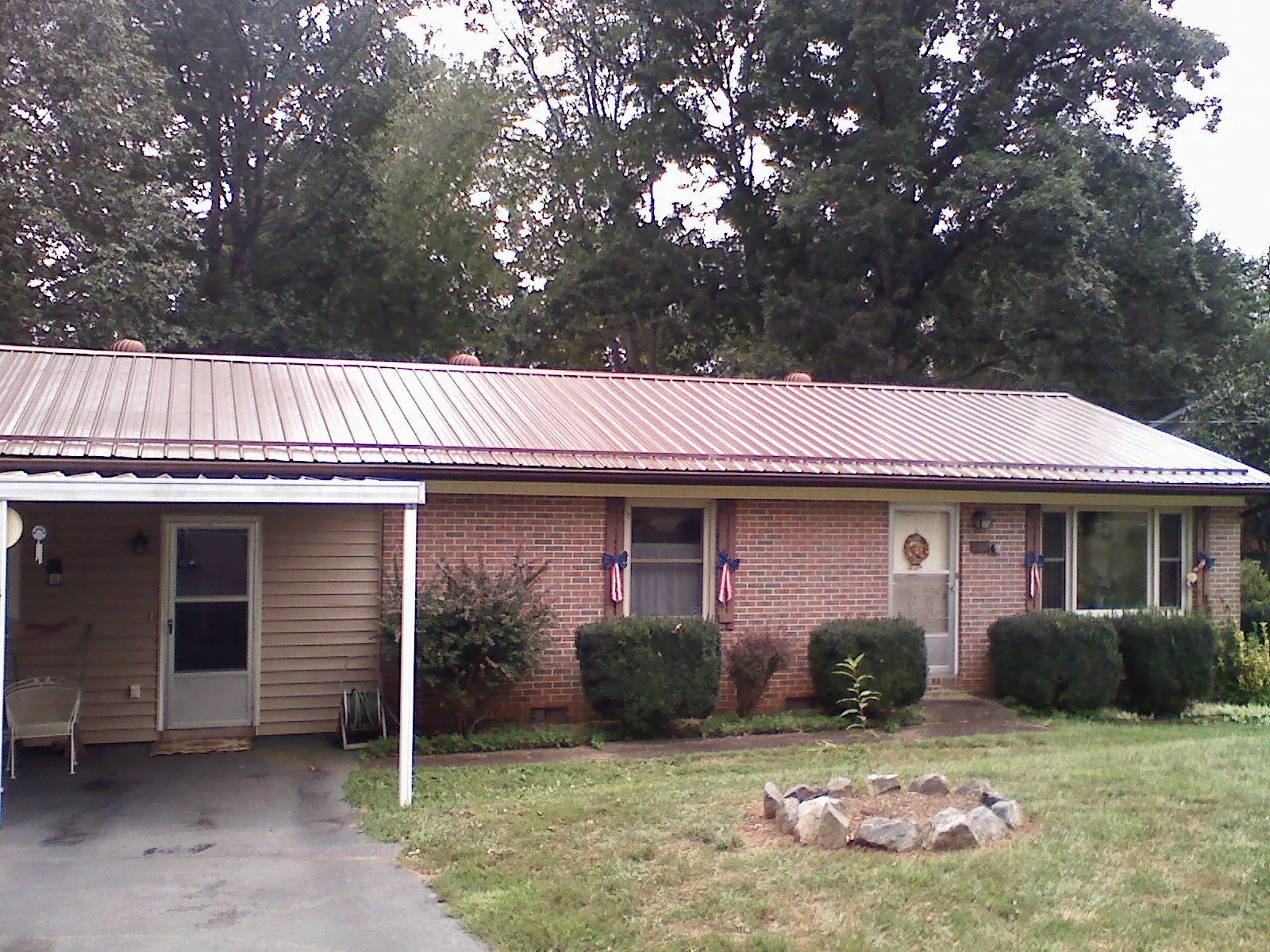 Bronze metal roof and carport on a brick ranch home — Roof Repair work by our crew in Wilder