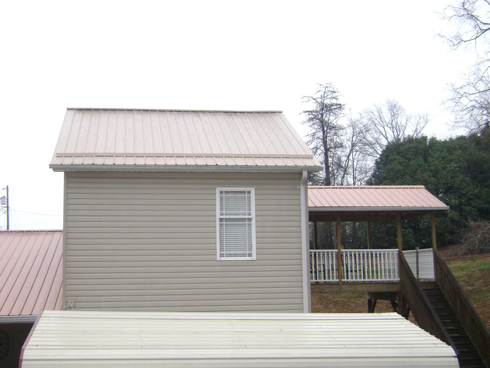 Tan metal roofs on a two story addition and attached porch, from a Roof Replacement job in Wilder